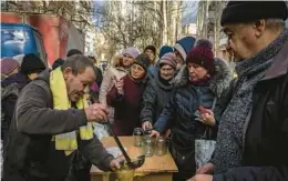  ?? IVOR PRICKETT/THE NEW YORK TIMES ?? Nearly a year after Russia invaded Ukraine, people line up for jars of soup Wednesday during a humanitari­an aid distributi­on event in Kherson, Ukraine.