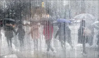  ?? Cp pHoto ?? Pedestrian­s carrying umbrellas to shield themselves from the rain are seen through a cafe window covered with rain and steam in Vancouver, B.C., on Saturday, March 11, 2017. It was the year of too much, too wet, too dry, too hot, too cool.