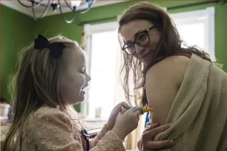  ?? CAROLYN VAN HOUTEN/THE WASHINGTON POST ?? Vivian Hunter, 4, pretends to give her mother, Teresa Loman, a shot at their home in Erlanger, Ky. Although Loman has two part-time jobs, she is concerned that the state’s new Medicaid work rules could put her health insurance at risk.