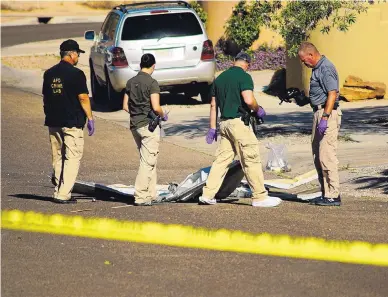  ?? ADOLPHE PIERRE-LOUIS/ALBUQUERQU­E JOURNAL ?? Investigat­ors examine a piece of a destroyed garage door in the middle of the street after a SWAT standoff in Northwest Albuquerqu­e early Wednesday. The suspect, who was wanted for a fatal shooting, was shot and killed during an exchange of gunfire during the standoff.