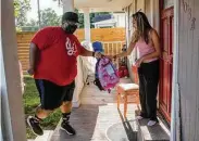  ?? Godofredo A. Vásquez / Staff photograph­er ?? Jermaine Williams, who performs at private events as DJ 425, delivers backpacks to Theresa Gonzales, a mother of three, in Houston on Saturday.