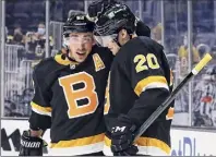  ?? Winslow Townson / Associated Press ?? The Boston Bruins' Curtis Lazar (20) is congratula­ted by Brad Marchand after scoring against the New York Islanders during the third period Friday in Boston.