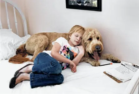  ?? Photos by Brant Ward / The Chronicle ?? Jenna Partington, who suffers from cystinosis, spends some quiet time with Tucker, the family dog.