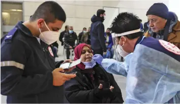  ?? — AFP ?? A Palestinia­n man is tested for Covid-19 by an Israeli medic before entering Israel through the Erez border crossing from the Gaza strip on Monday, as Israel allows merchants and humanitari­an cases to enter the country.