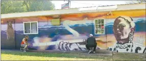  ?? Westside Eagle Observer/SUSAN HOLLAND ?? Samuel Hale, Pineville, Mo., artist, and Mark Lester Jr., owner of 420 thang, stretch a measuring tape to check dimensions of a mural Hale is painting on the side of the Blended Ends Salon/420 thang business building in Gravette. The mural features a bear, a giant serpent and a beautiful Cherokee warrior woman smoking a pipe, all elements in a Cherokee Indian legend.