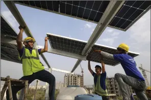  ?? (AP/Manish Swarup) ?? Workers of Solar Square put up a panel on the rooftop of a residence in Gurugram on the outskirts of New Delhi earlier this month.