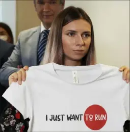  ?? Associated Press ?? Belarusian Olympic sprinter Krystsina Tsimanousk­aya, who arrived in Poland on Aug. 4 fearing reprisals at home after criticizin­g her coaches at the Tokyo Games, holds up an Olympics-related T-shirt after her news conference in Warsaw.