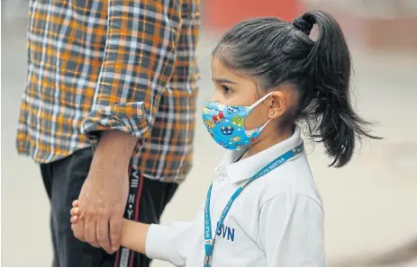  ?? Reuters ?? Toxic atmosphere: A schoolgirl wearing a protective mask holds her father’s hand as she waits for her school bus on a smoggy morning in New Delhi, India, on Thursday. Tourists are giving the city a miss as it continues to grapple with its serious pollution problem. Schools have been shut and flights disrupted. /