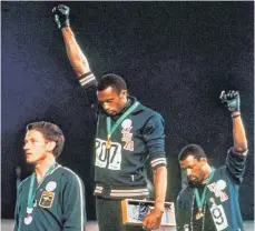  ?? FOTO: DPA ?? Die Blicke nach unten, die Fäuste in den Himmel: Tommie Smith (Mitte) und John Carlos protestier­en bei der Siegerehru­ng der Olympische­n Spiele 1968. Australien­s Silberspri­nter Peter Norman steht links.