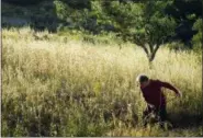  ?? CALEB BURDEAU VIA AP ?? The writer Cain Burdeau’s father, Bob Burdeau, cutting grass on his property near Martina Franca in Puglia, Italy. He has cut the grass on his property for many years with a scythe.