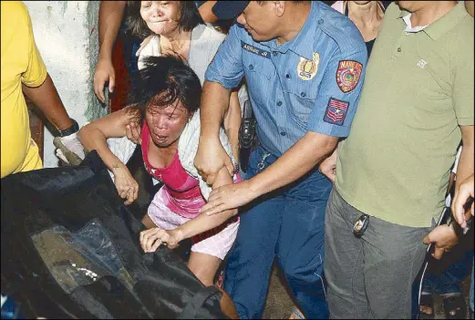  ?? JOVEN CAGANDE ?? Merlie Meneses reacts upon seeing funeral parlor workers carry the body of her son, Melvin Meneses, in a body bag after he was killed by police officers during a drug bust in Pandacan, Manila Wednesday night.