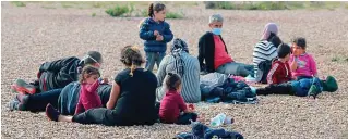  ??  ?? New arrivals: A group of migrants on the beach at Dungeness, Kent