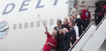  ?? BLOOMBERG PHOTO BY MIKE KANE ?? Delta Air Lines crew members take a selfie photograph while disembarki­ng from a Boeing 747 after landing at Paine Field in Everett, Washington, on Monday.