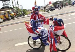  ??  ?? ACCRA: A supporter rides a bicycle wearing outfit designed with colors of the opposition New Patriotic Party during the grand campaign rally of the party in Accra. — AFP