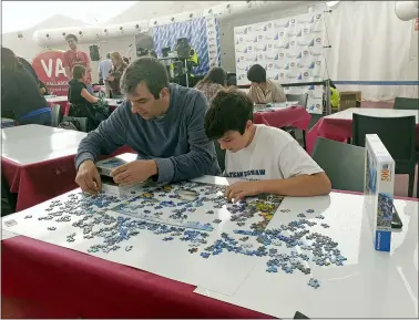  ?? JULIE JACOBS VIA AP ?? A.J. Jacobs and his son Zane, 13, are shown during an event at the 2019World Jigsaw Puzzle Championsh­ip in Spain. There were 40 countries represente­d at this competitio­n. Jigsaw puzzles are in vogue. There are puzzles left out in offices and at coffee shops, puzzle clubs and competitio­ns online, and artistic, mind-bending puzzles that sell for thousands of dollars.