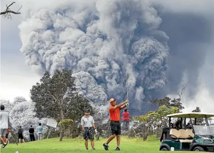  ?? AP ?? People play golf as an ash plume rises in the distance from the Kilauea volcano on Hawaii’s Big Island.