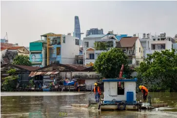  ?? IMAGES: Shuttersto­ck ?? ABOVE: Workers cleaning the Mekong River from a boat in a poor neighbourh­ood of Ho Chi Minh City, Vietnam