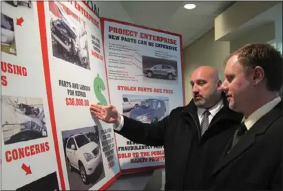  ?? ERICA BAJER QMI Agency Niagara ?? Sgt. Dave Shennan points out a wrecked vehicle on a Project Enterprise poster used to explain a complicate­d chop shop and fraud ring busted by police this week. Det. Const. Dave Marynuik looks on.