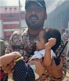  ??  ?? Relief: Rescuer carries child from building rubble