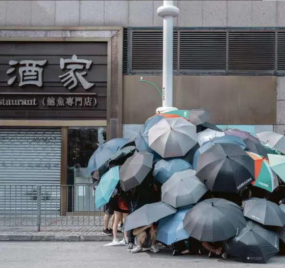  ?? Photo Thaddé COMAR ?? A Hongkong, en 2019. Des militants s’abritent pour saboter un système de reconnaiss­ance faciale.