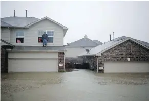  ?? — BLOOMBERG ?? A man stands on the second storey ledge of a house while waiting to be rescued from flood waters that continue to rise due to Hurricane Harvey in Spring, Texas, on Monday.