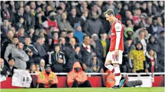  ??  ?? Cold comfort: Mesut Ozil cuts a lonely figure at Arsenal despite backing from supporters (below) on Thursday night