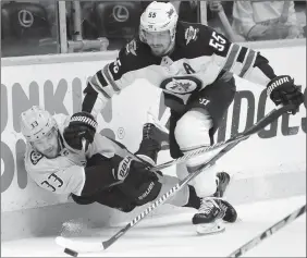  ?? The Associated Press ?? Nashville Predators’ left-winger Viktor Arvidsson tries to pass the puck as he is checked by Winnipeg Jets’ centre Mark Scheifele on Sunday in Tennessee.