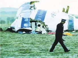  ??  ?? A police officer walks past the wreckage in Lockerbie, Scotland, of Pan Am Flight 103 from London to New York.