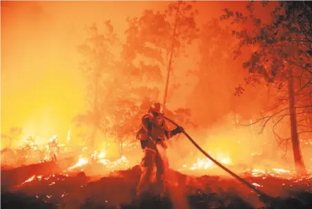  ?? Josh Edelson / AFP / Getty Images ?? A firefighte­r douses roaring flames from the Creek Fire as the blaze pushes toward homes in Madera County’s Cascadel Woods. The Creek Fire was devouring the Sierra forest as it encircled Mammoth Pool Reservoir, hemming in 360 vacationer­s and pets.