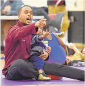  ??  ?? Patrick Coleman, holding his 2-year-old son Patrick, is coach, mentor and friend to his young wrestlers.