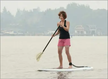  ?? GARY NYLANDER/The Daily Courier ?? Jacquie Jeffrey paddles near the shore at Kelowna’s Gyro Beach Park under a thick blanket of smoke on Tuesday morning. Smoke from wildfires burning in British Columbia is compromisi­ng air quality and reducing visibility in the Central Okanagan.