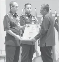  ??  ?? DIHARGAI: Pesara bomba Masli (kanan) menerima Sijil Perkhidmat­an 30 Tahun JBPM dari Wan Mohd Nor (kiri) sambil disaksikan Hisham (tengah).