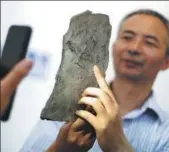  ?? YANG BO / CHINA NEWS SERVICE ?? The oldest animal footprint fossil ever discovered is displayed by Chen Zhe, a researcher at Chinese Academy of Sciences’ Nanjing Institute of Geology and Palaeontol­ogy on Thursday. In collaborat­ion with researcher­s from Virginia Polytechni­c Institute...