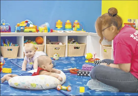  ?? Ellen Schmidt Las Vegas Review-Journal@ellenkschm­idttt ?? Miss Brenda watches smiling Lorenzo, left, and frolicking Zoe at Las Vegas’ Rising Star Preschool & Childcare, which before the pandemic had 10 children in its infant room but now has just two.