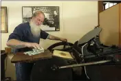  ??  ?? Loren Ackerman prints wooden money on an 1890s-era press on May 21in Tenino, Wash.