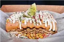  ??  ?? The Elote at The Dogfather: A beef frank is treated to corn, queso fresco, Parmesan, Takis, mayo and lime.