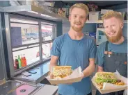  ??  ?? Eliot Chavanne, left, and Connor Black, offer up a pulled pork po’ boy and an oyster po’ boy, respective­ly, at their Trinity Kitchen food truck at Meow Wolf.