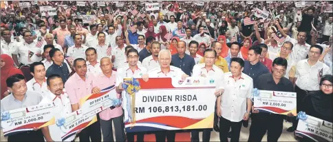  ??  ?? Najib (centre) holding a mock cheque of RM106.81 million in ‘duit raya’ via dividends for 33,864 smallholde­rs nationwide. — Bernama photo