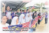  ??  ?? KIBAR: Zulhanin mengibarka­n bendera bersama pelajar-pelajar sekolah.