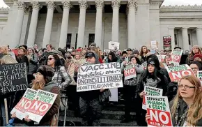  ?? AP ?? Protesters hold signs at a rally at the Capitol in Olympia, Washington, to oppose a proposed bill that would remove parents’ ability to claim a philosophi­cal exemption to opt their school-age children out of the combined measles, mumps and rubella vaccine.