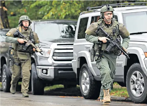  ??  ?? Police rapid response team members, above, at the site of the mass shooting at the synagogue in Squirrel Hill, Pittsburgh, below