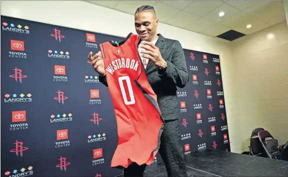  ?? [DAVID J. PHILLIP/ THE ASSOCIATED PRESS] ?? Former Oklahoma City Thunder guard Russell Westbrook grabs his Rockets jersey after Friday's news conference in Houston.