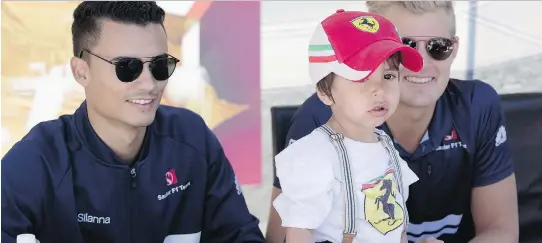  ?? PHOTOS: ALLEN MCINNIS ?? A two-year-old boy poses for a picture with Sauber’s Pascal Wehrlein, left, and Marcus Ericsson at Circuit Gilles Villeneuve during race weekend festivitie­s.