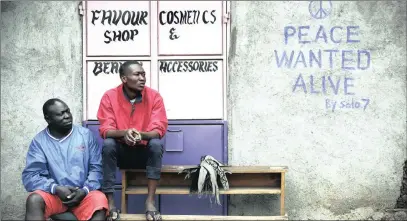  ?? PICTURE: EPA ?? Men sit in front of a wall with a message of peace painted recently by local street artist Solomon Muyundo, also known as Solo7, on its door in Kibera slum, one of the opposition leader Raila Odinga’s stronghold­s in the Kenyan capital, Nairobi, on...