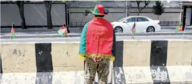  ?? Agence France-presse ?? A security personnel wraps an Afghan national flag around himself on the occasion of the National Flag Day in Kabul on Thursday.