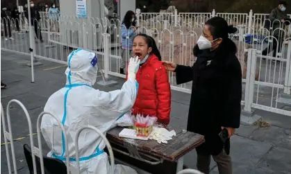  ?? Photograph: Jade Gao/AFP/Getty ?? A health worker takes a swab sample from a girl to be tested for Covid at a collection station in Beijing.