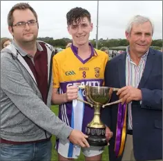  ??  ?? Conall O Crualaoich receives the cup from Dean Goodison (People Newspapers) and Bobby Goff (Coiste na nOg Chairman).
