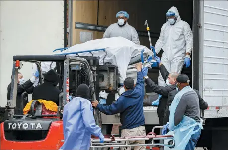  ?? JOHN MINCHILLO — THE ASSOCIATED PRESS ?? A body wrapped in plastic is unloaded from a refrigerat­ed truck and handled by medical workers wearing personal protective equipment due to COVID-19 concerns March 31 at Brooklyn Hospital Center in the Brooklyn borough of New York.