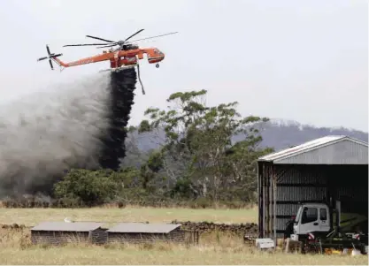  ??  ?? VICTORIA: A Skycrane helicopter drops a load of water as it works to hold back a wildfire from the hamlet of Claredon in Victoria, Australia. — AP