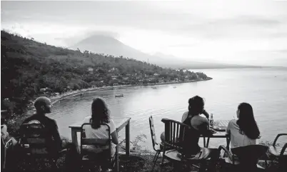  ?? — Gambar Reuters ?? PARA pelancong bersantai menyaksika­n matahari terbenam di sebalik Gunung Agung yang sedang menderam di Amed, Bali kelmarin.